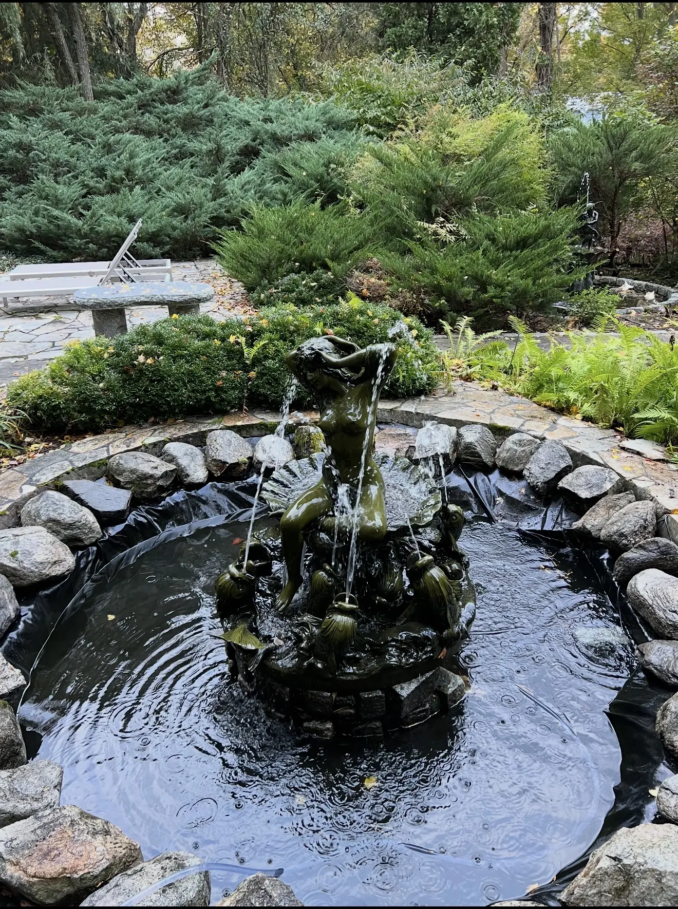 Garden fountain with bronze statue and stone border